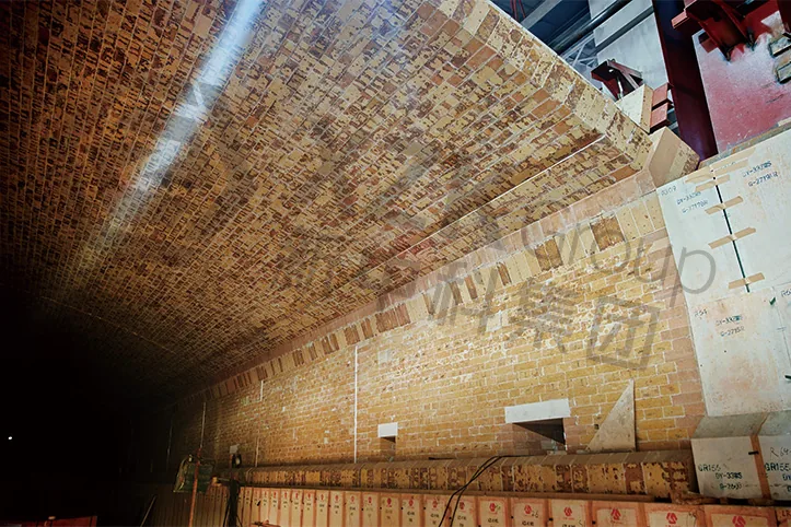 Crown and crown corner lining viewed along the side wall during a rebuild — dense brickwork on the hot face with insulating courses behind.
